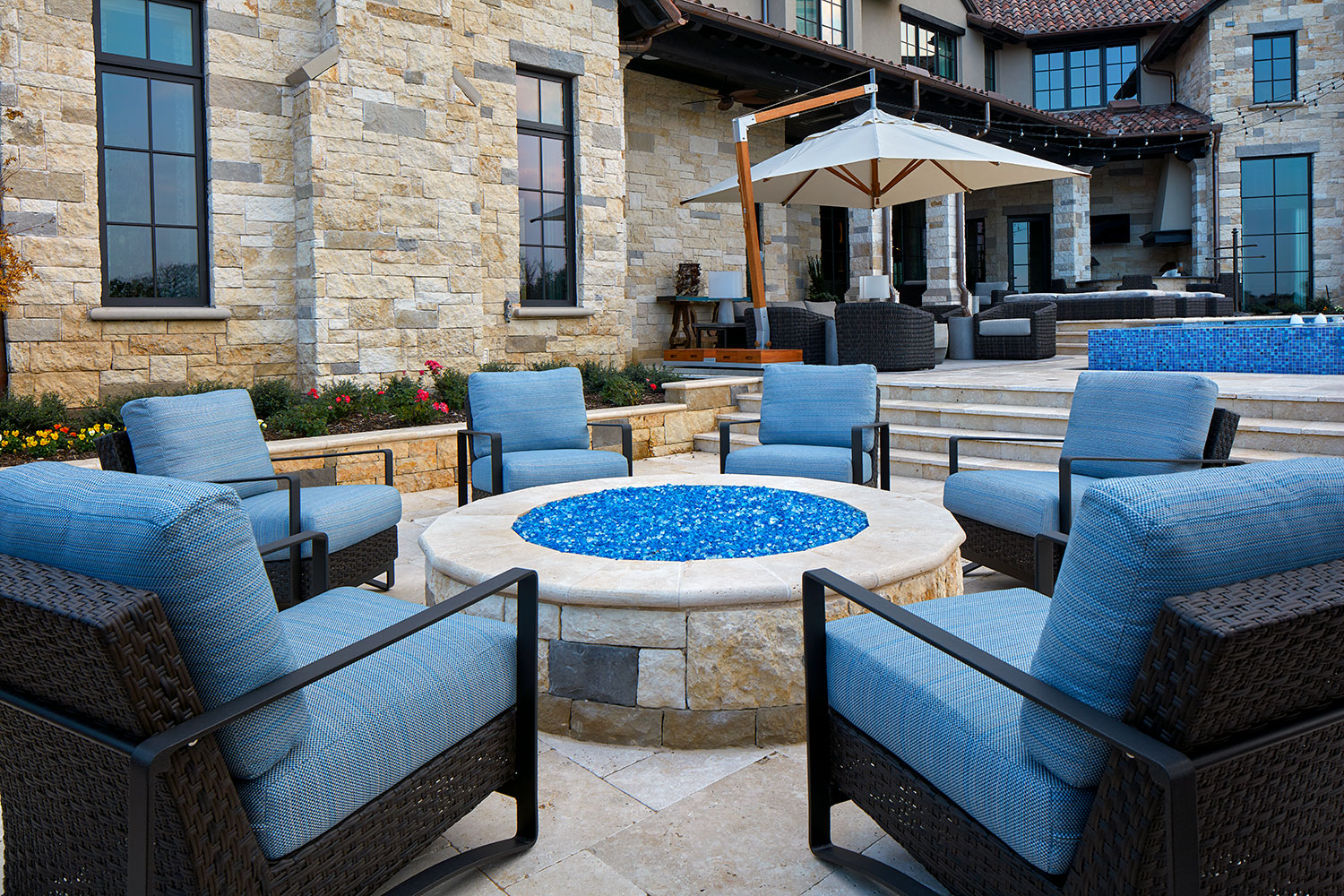 Backyard Stone Fire Pit With Woven, Upholstered Arm Chairs