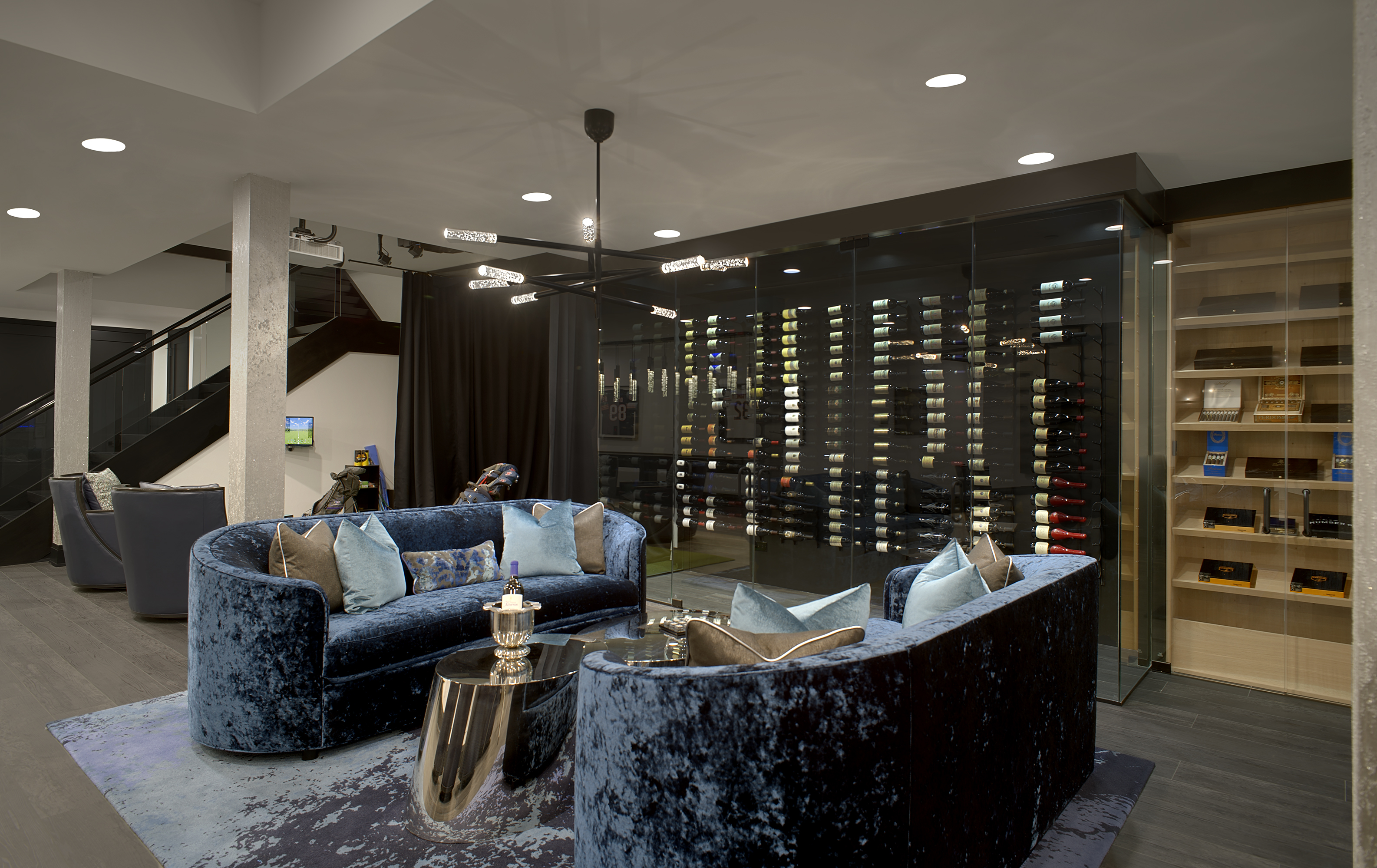 glass wine cellar with adjacent humidor and matching blue velvet sofas